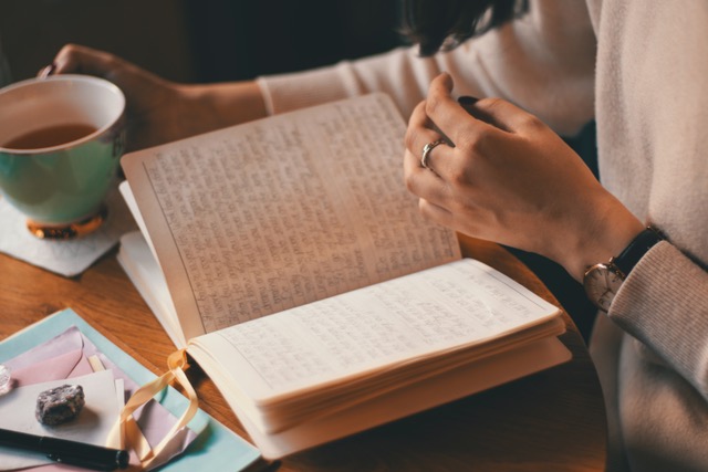 Woman writes in journal with cup of tea